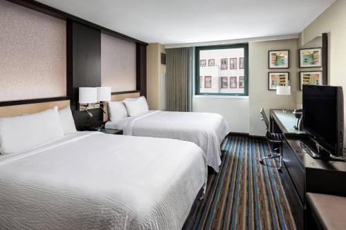 a hotel room with two beds and a flat screen tv at Courtyard New York Manhattan/Times Square in New York