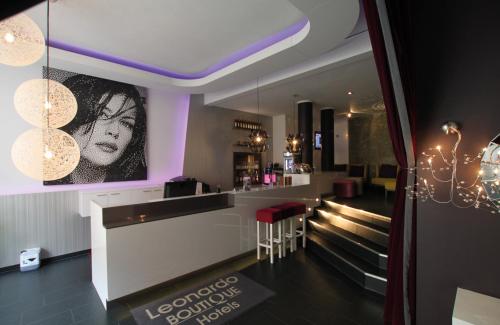a bar in a restaurant with purple lighting at Leonardo Boutique Hotel Munich in Munich