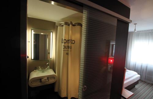 a bathroom with a sink and a shower with a mirror at Leonardo Boutique Hotel Munich in Munich