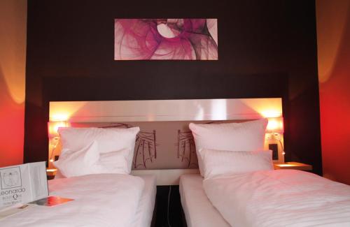 two beds in a hotel room with white sheets at Leonardo Boutique Hotel Munich in Munich