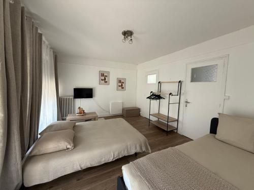 a white bedroom with two beds and a window at Studio cosy en hypercentre de Louviers in Louviers