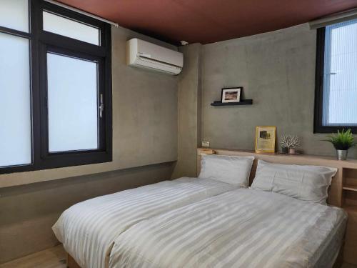 a bedroom with a white bed with two windows at In68 House in Ch'ih-k'an-lou