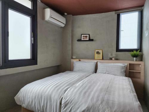 a bedroom with a large bed with two windows at In68 House in Ch'ih-k'an-lou