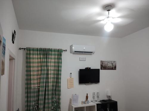 a room with a ceiling fan and a television on a wall at Doribella Holiday House in Finale