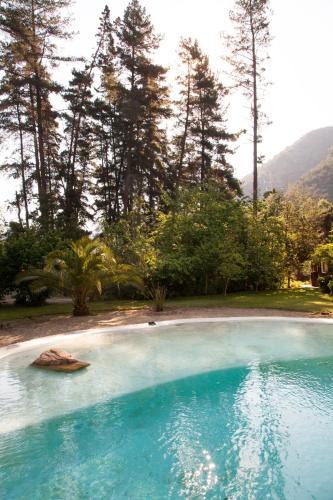 a large pool of blue water with trees in the background at La Ermita Hostal in Santiago