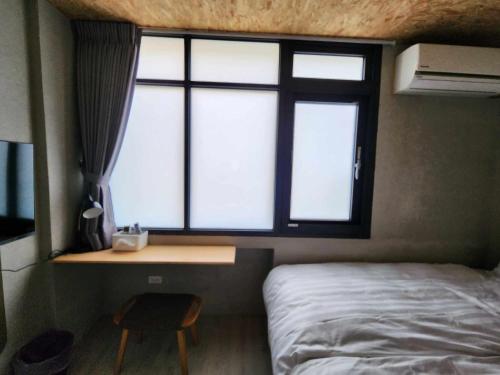 a bedroom with a bed and a desk and a window at In68 House in Ch'ih-k'an-lou