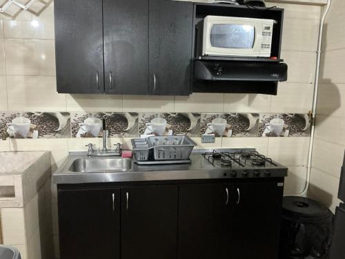una cucina con lavello e microonde di Aparta suite Torre de Prado 402 a Medellín