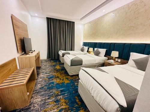 a hotel room with two beds and a television at فندق اللؤلوة الزرقاء Blue Pearl Hotel in Quai