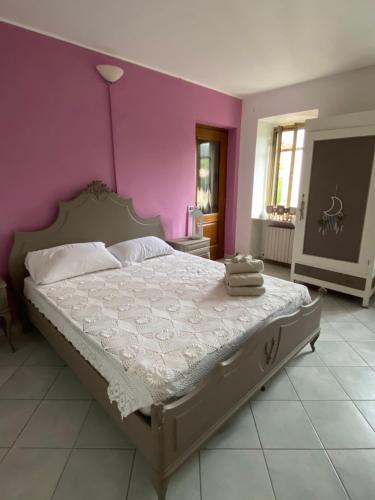 a bedroom with a large bed with a purple wall at La Cà di Carol in Tollegno