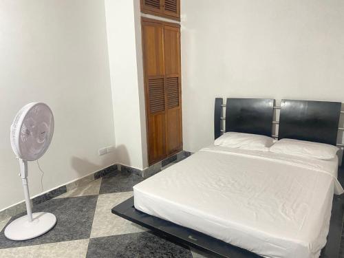 ein Schlafzimmer mit einem weißen Bett und einem Ventilator in der Unterkunft Casa MAVA in Mariquita