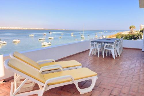 a balcony with a table and chairs and a view of the water at Beach House on Faro Island with a Dreamy Terrace and 7 Beds for the Perfect Escape in Faro