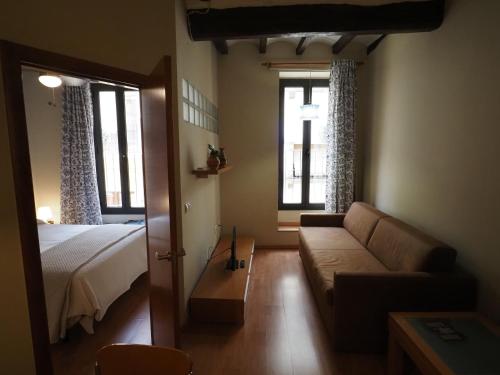 a living room with a couch and a bed and windows at Apartaments El Jaç in Montblanc
