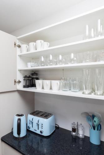 a kitchen counter with cups and glasses on shelves at 2 Storey Villa, Games room, Ski storage in Methven