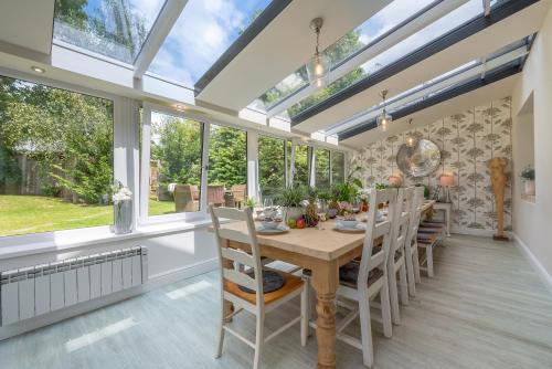 a dining room with a table and chairs and windows at Lower Shockerwick Lodge in Bath