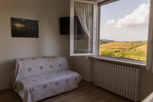 a bedroom with a chair and a large window at I Pesci De Boschi in Borgo Priolo