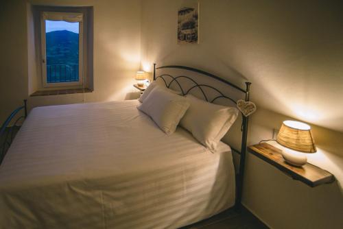 a bedroom with a white bed with a window at Locanda Vecchio Caseificio in Toano