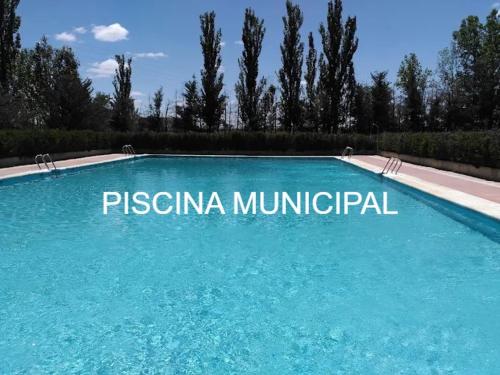 une grande piscine bleue avec les mots piscina municipal dans l'établissement Apartamentos Rural La Perla, à Becilla de Valderaduey