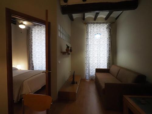 a bedroom with a bed and a couch and a window at Apartaments El Jaç in Montblanc
