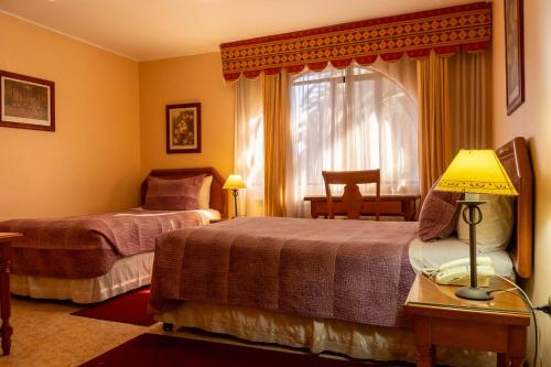 a hotel room with two beds and a window at Hotel Mosul in Concepción