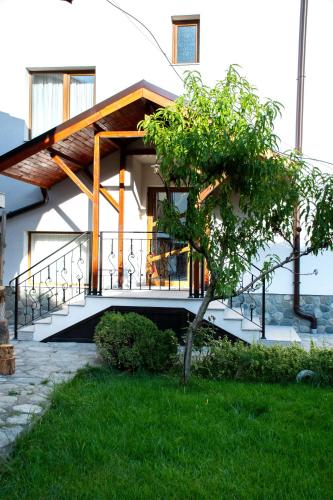 a house with a balcony with a tree in the yard at Орбелус in Bansko
