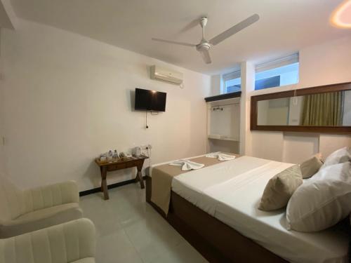 a bedroom with a bed and a chair and a television at Sky Garden Kandy in Kandy