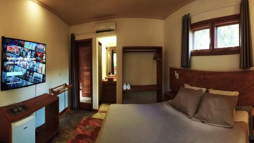 a bedroom with a bed and a flat screen tv at Pousada Vila Araticum in Santo André