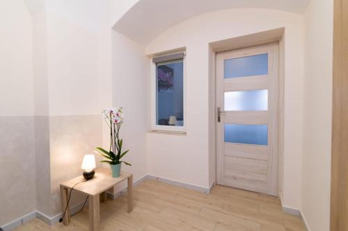 a hallway with a door and a table with flowers at Storczyk in Duszniki Zdrój