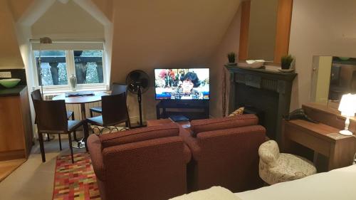 a living room with a fireplace and a tv at Cavendish Superior Suite in Bakewell