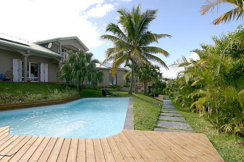 a swimming pool in front of a house with palm trees at Villa Romeo in Étang-Salé