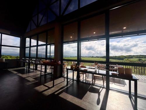 a dining room with tables and large windows at GrandWara Khao Yai แกรนด์วารา เขาใหญ่ in Ban Nong Song Hong