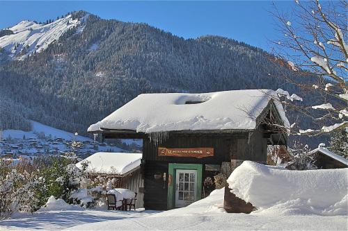 a building covered in snow with a mountain in the background at Micro-lodge, Le Petit Nid d'Amour in Montriond