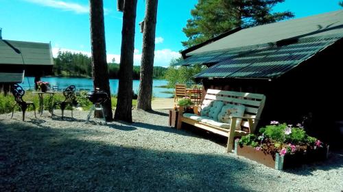 a bench sitting next to a table and a lake at Rustika strandstugor utanför Rättvik in Rättvik