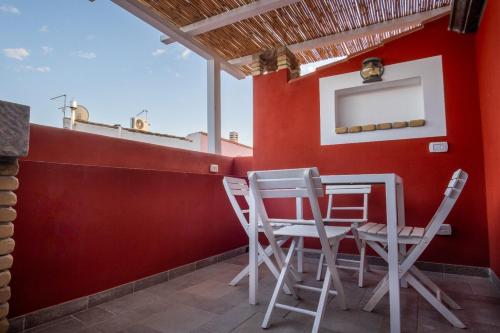 a patio with chairs and a red wall at Casa Ancora in Carloforte