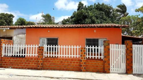 a small orange house with a white fence at Casa Santos in Santo Amaro