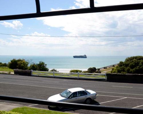 a white car driving down a road near the ocean at Accommodation Portland Victoria in Portland