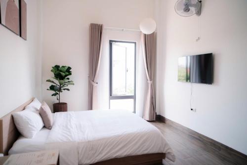 a white bedroom with a bed and a window at Glory 2 Hue Homestay in Hue