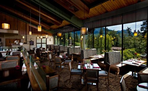 a restaurant with tables and chairs and windows at Bow View Lodge in Banff