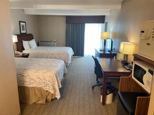 a hotel room with two beds and a desk at Hotel O Suites & Conference Centre Urbana-Champaign University in Urbana