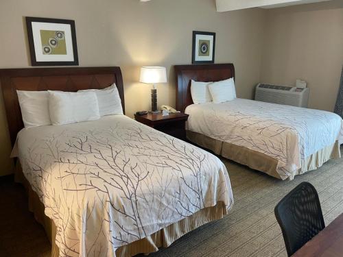 a hotel room with two beds and a table at Hotel O Suites & Conference Centre Urbana-Champaign University in Urbana