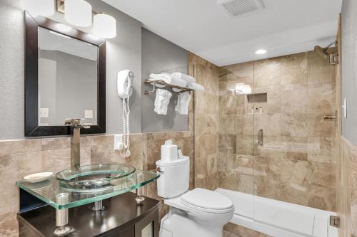 a bathroom with a toilet and a glass sink at Hotel O Suites & Conference Centre Urbana-Champaign University in Urbana