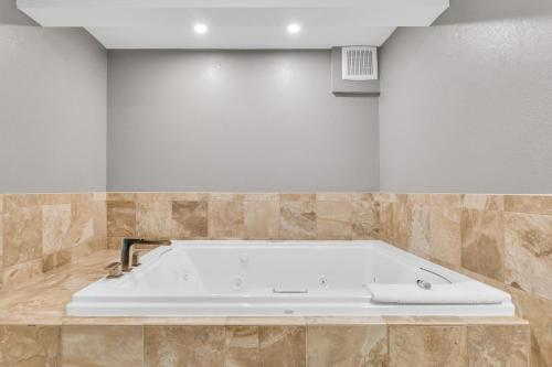 a white bath tub in a room with tiles at Hotel O Suites & Conference Centre Urbana-Champaign University in Urbana