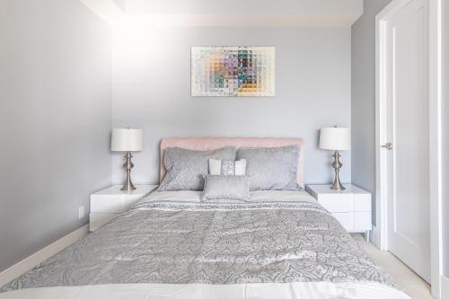 a white bedroom with a bed and two lamps at 1 Bedroom 26 Floor DT near CN Tower in Toronto