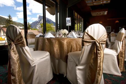 a table with white and gold chairs with bows at Banff Park Lodge in Banff
