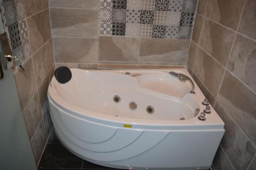 a white bath tub in a tiled bathroom at Marina Palace Hotel in Al Madinah