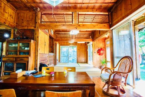 a living room with a wooden table and chairs at 今帰仁古民家の宿 つばめや in Nakijin