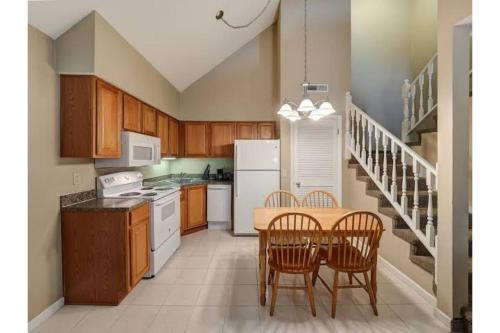 a kitchen with a table and chairs and a white refrigerator at Hotel O Suites & Conference Centre Urbana-Champaign University in Urbana