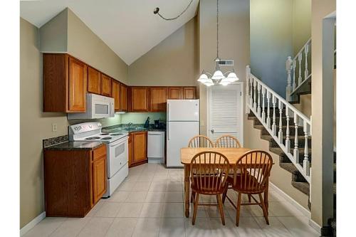 a kitchen with a table and chairs and a white refrigerator at Hotel O Suites & Conference Centre Urbana-Champaign University in Urbana