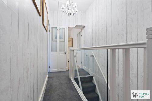 a hallway with stairs and a chandelier at Seagull Cottage in Hunstanton