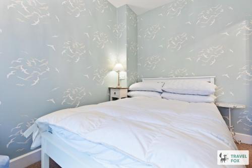 a bedroom with blue walls and a bed with white sheets at Seagull Cottage in Hunstanton