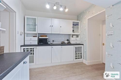 a kitchen with white cabinets and a counter top at Seagull Cottage in Hunstanton